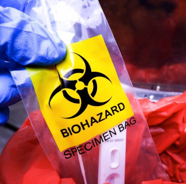 Gloved hand holding a biohazard specimen bag