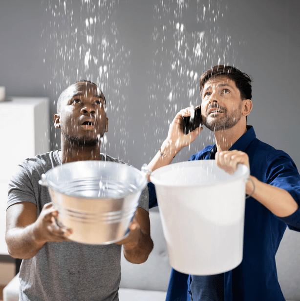 Homeowners catching water from a ceiling leak during a water damage emergency