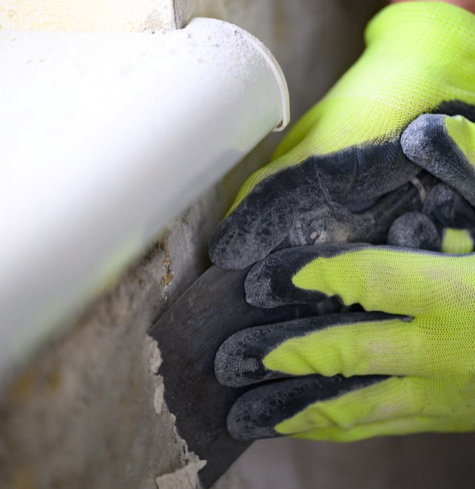 Mold Remediation Technician Removing Moldy Drywall Knoxville Gloved mold remediation technician removing mold-contaminated drywall behind a pipe in a Knoxville home