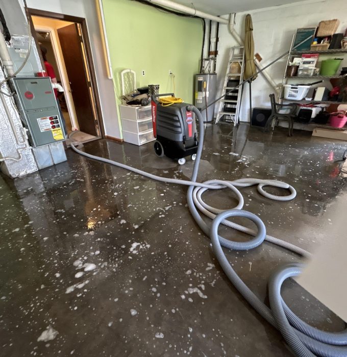 Sewage Cleanup Knoxville TN Water extraction hoses removing standing water from a flooded utility room in a Knoxville home